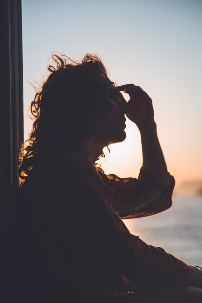 Photo by Matteo Vistocco man holding forehead under sunset