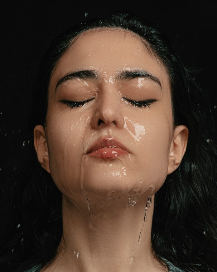 Photo by Behrooz a woman with her eyes closed covered in water