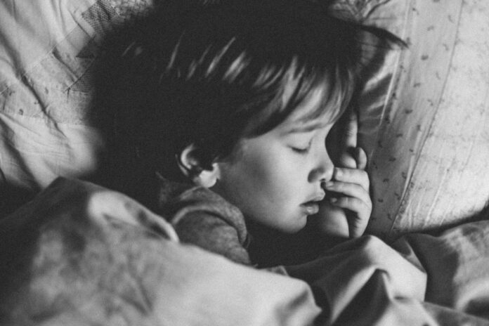 Photo by Annie Spratt grayscale photo of girl sleeping on white pillow