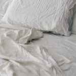 당신의 잠, 더 깊고 달게 자는 신 트렌드…한국인의 ‘슬리핑 루틴’ 바꾸는 비결 A rumpled white duvet and pillows on a bed.