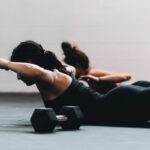 바쁜 일상 속 필라테스, 내 몸을 지키는 건강 루틴으로 자리 잡다 woman in black tank top and black leggings lying on black floor